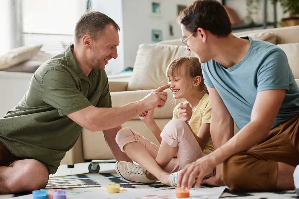 Two dads painting with their daughter