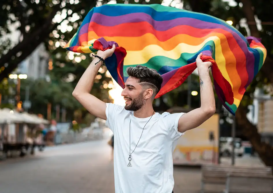 A person holding up a rainbow flag behind his back